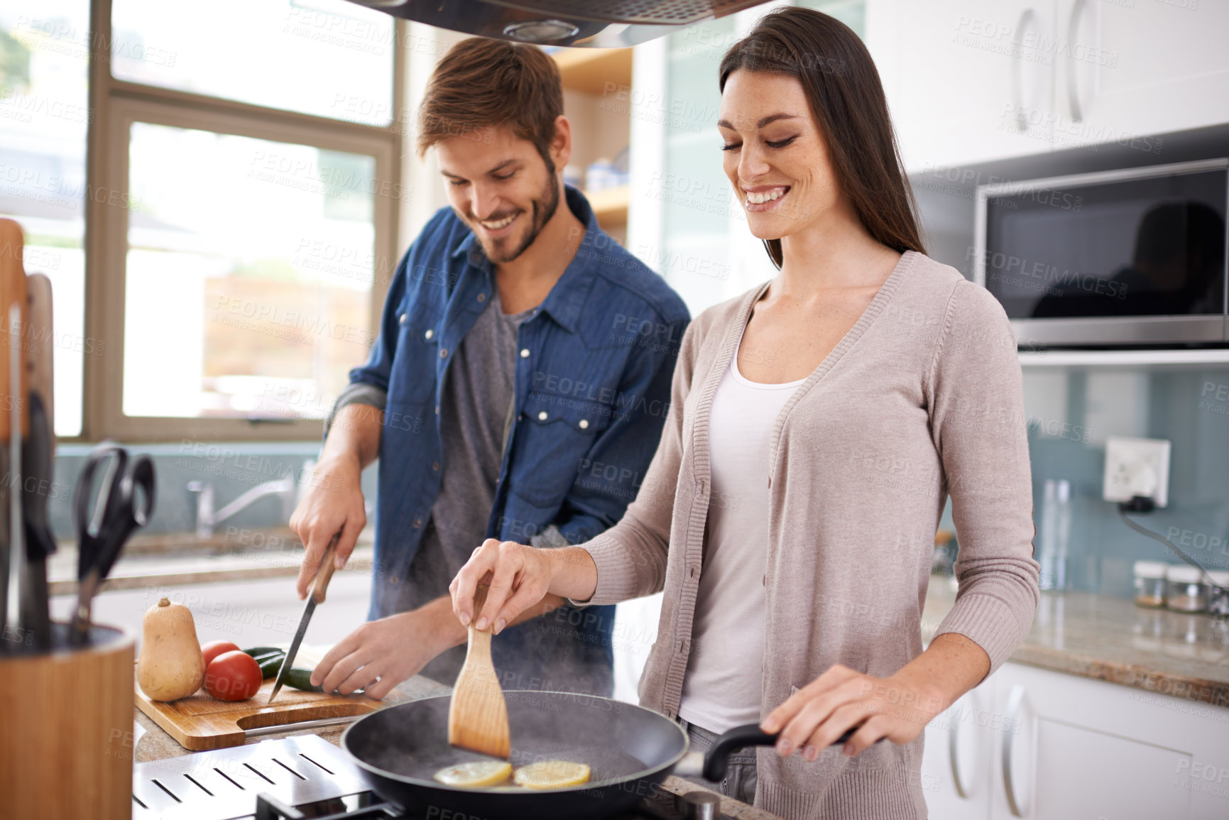 Buy stock photo Happy couple, food and cooking together in the kitchen on pan with healthy organic nutrition or diet for dinner at home. Man helping woman with smile in happiness making meal with vegetables on stove