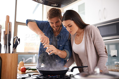 Buy stock photo A young couple making dinner together at home