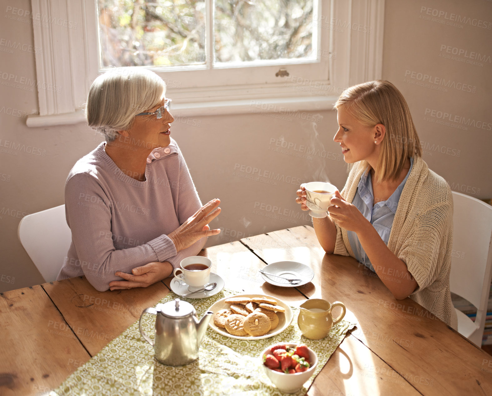 Buy stock photo Talking, grandmother and woman with tea in home for brunch, bonding or visit in retirement. Senior, grandma and girl on coffee break with food, conversation and relax on holiday or vacation morning