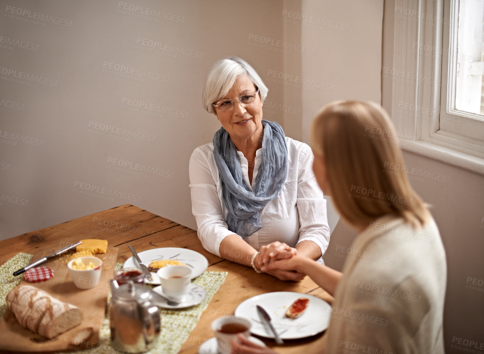Buy stock photo Mother, daughter and home with smile for holding hands in table for bonding, support and visit. Meal, family and tea with food for conversation on break, leisure and happiness for coffee and care.