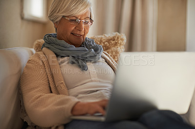 Buy stock photo A happy senior woman working on her laptop at home
