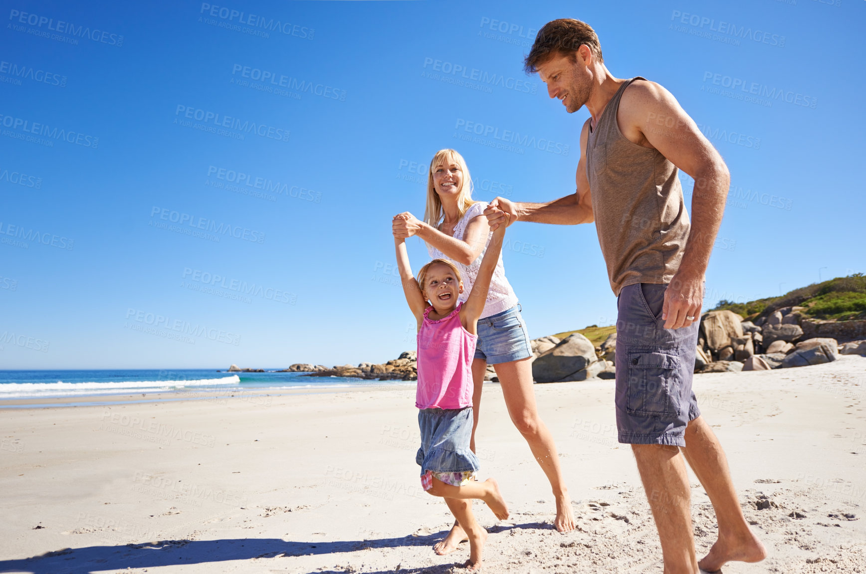 Buy stock photo Love, holding hands and happy family at a beach with swing, support and care while bonding in nature. Freedom, travel and kid with parents at the ocean for morning games, fun or adventure at the sea