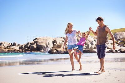 Buy stock photo Shot of a happy young family taking a walk on the beach