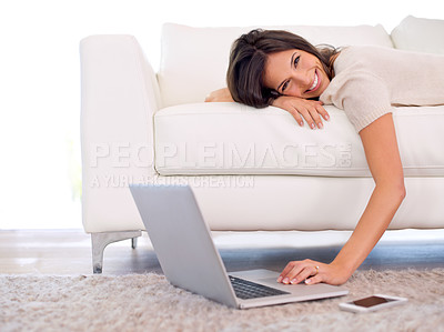 Buy stock photo Cropped shot of a gorgeous young woman lying on a couch using a laptop
