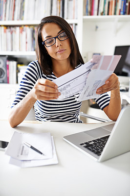 Buy stock photo Cropped shot of an attractive young woman going through bills in her home study