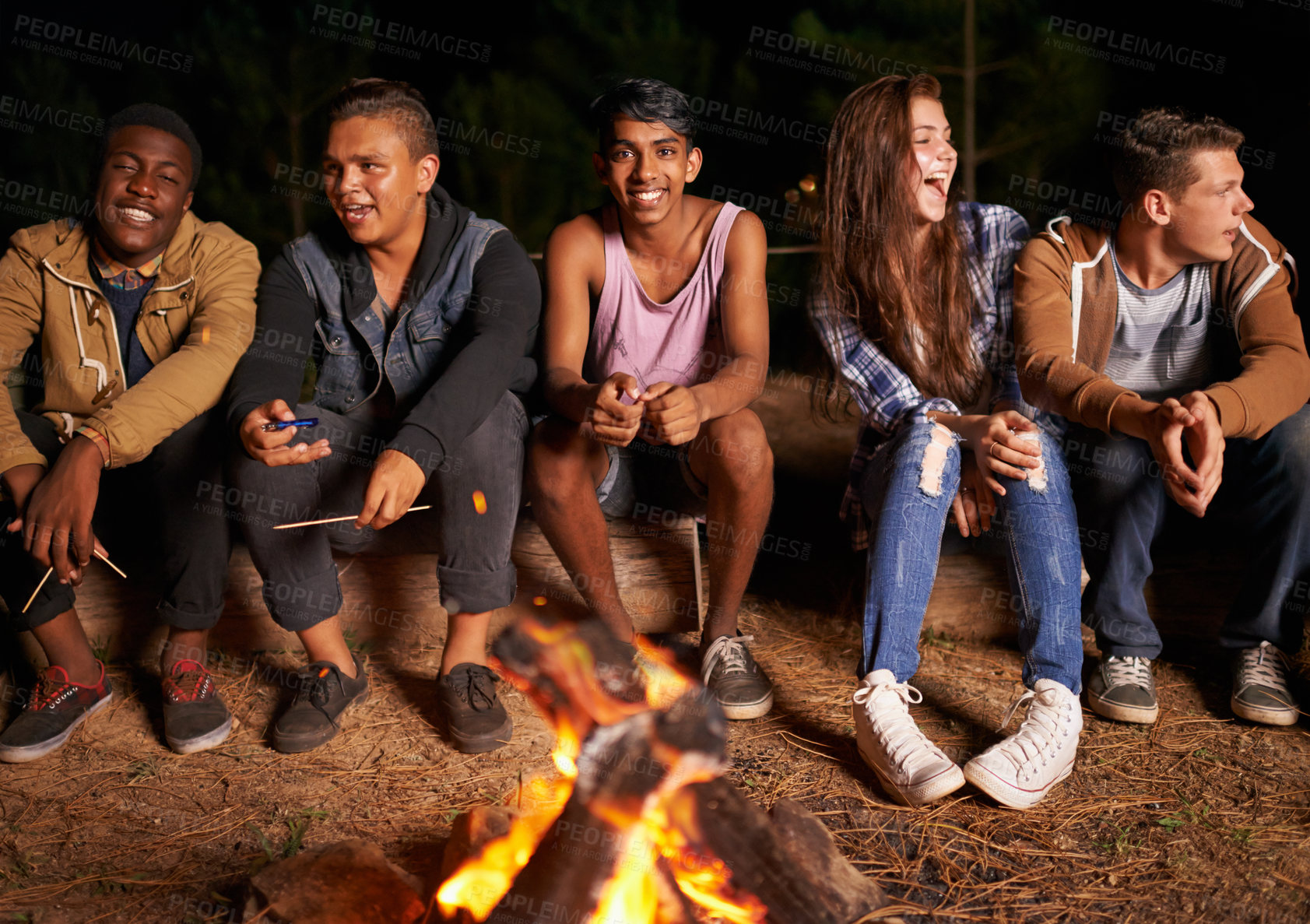 Buy stock photo A group of friends enjoying spending time together beside a fire