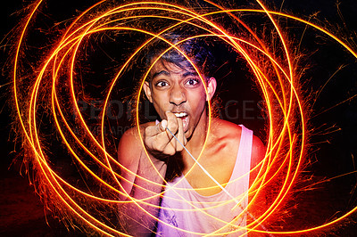 Buy stock photo Cropped shot of a teenage boy sticking out his tongue and playing with a firework