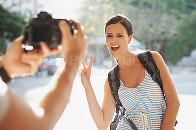 Buy stock photo Tourist, woman and photography with peace sign for travel, sightseeing or memories on holiday or vacation in street. People, person or funny face in city for explore, tourism or journey in urban town