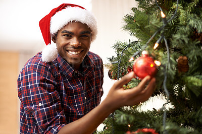 Buy stock photo Portrait, happy and black man with Christmas tree in living room of home for decoration or holiday. Celebration, December or smile and festive young person in apartment with Santa hat for tradition