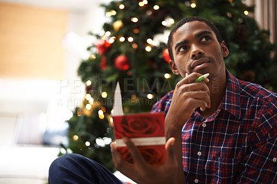 Buy stock photo African, man and thinking for christmas, card and holiday with message for vacation. Person, pen and idea for writing, home and tree with decorations, communication and creative at home for gift