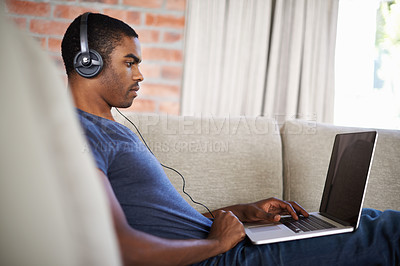 Buy stock photo Man, internet and music with laptop on sofa for movie streaming, podcast and online games with listening. Young, black person and technology with headphones for relax, studying and learning in lounge