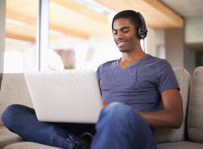 Buy stock photo Man, face and music with laptop on couch for internet streaming, podcast and online research with smile. Student, black person and technology with headphones for relax, studying and learning in home