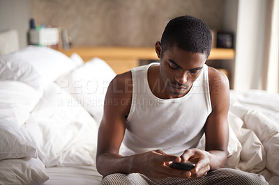 Buy stock photo Black man, typing and bed with phone for communication, social media or networking at home. African male person on mobile smartphone in morning for online chatting, texting or app in bedroom at house