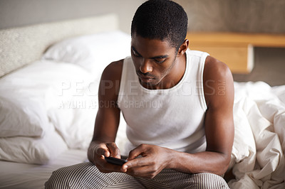 Buy stock photo Black man, typing and bed with phone for social media, networking or communication at home. African male person on mobile smartphone in morning for online chatting, texting or app in bedroom at house