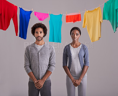 Buy stock photo Portrait, people and laundry in studio with clothes, hanging and drying on washing line. Black person, man and woman in marriage or dating, cleaning and routine while standing on gray background
