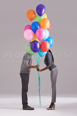 Buy stock photo Couple, party and celebration with balloons for event, birthday or romance on a gray studio background. Man and woman holding colorful blowups of helium for art, date or anniversary on mockup space