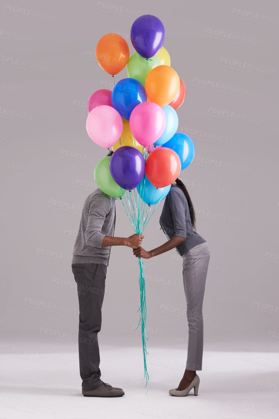 Buy stock photo Couple, party and celebration with balloons for event, birthday or romance on a gray studio background. Man and woman holding colorful blowups of helium for art, date or anniversary on mockup space