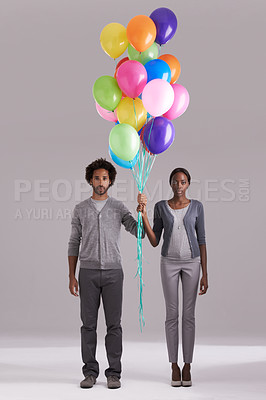 Buy stock photo Couple, portrait and party with balloons for celebration, event or romance on a gray studio background. Man and woman holding colorful blowups of helium for art, date or anniversary on mockup space