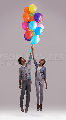 Buy stock photo Couple, float and flying with bunch of balloons for event, birthday or romance on a gray studio background. Man and woman holding colorful blowups of helium up for date or anniversary on mockup space