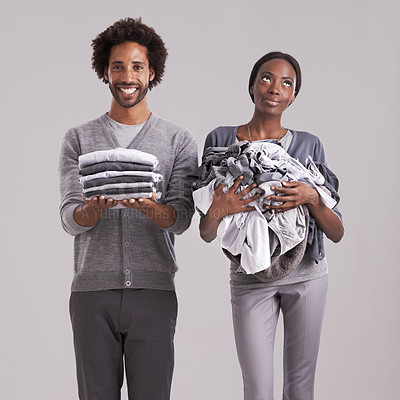 Buy stock photo Young, couple and laundry or clothes for helping, support and thinking of house, task or home management in studio. African man and woman with domestic ideas for gender equality on a gray background