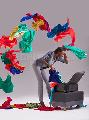 Buy stock photo Studio shot of a young woman throwing her multi colored clothes out of a suitcase