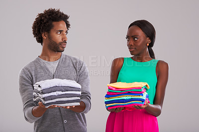 Buy stock photo People, studio and pile of laundry in hand for neat, cleaning day or washing clothes together. Couple, surprise and shocked for organised wardrobe with color choice, fashion or ocd on grey background