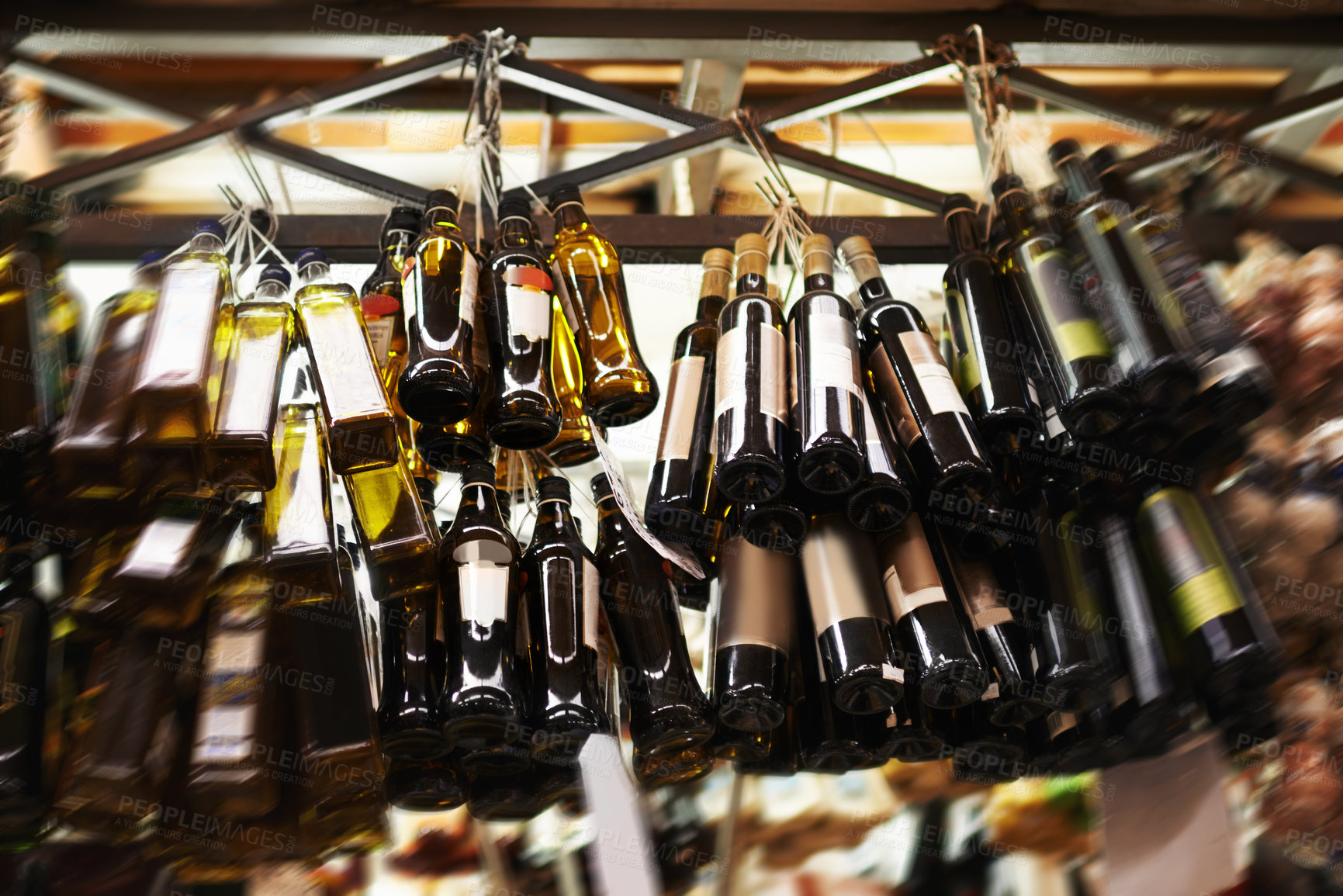 Buy stock photo Hanging bottles of olive oil at a food market