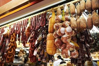 Buy stock photo Hooks, butcher and dry meat in shop for traditional food, groceries or products in Germany. Supermarket, deli and fermented or smoked sausages hanging in row for production in grocery store. 