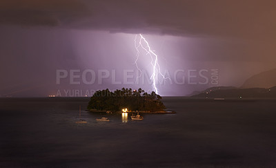 Buy stock photo Shot of lightning hitting a small island in a night time storm