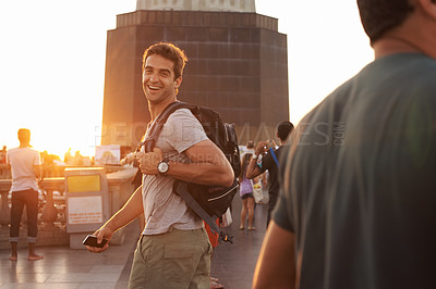Buy stock photo Portrait, smile and man with backpack sunset, tourist and travel abroad for adventure or vacation. Happy person, laughing and holiday journey in city with casual outfit, smartphone and joyful face