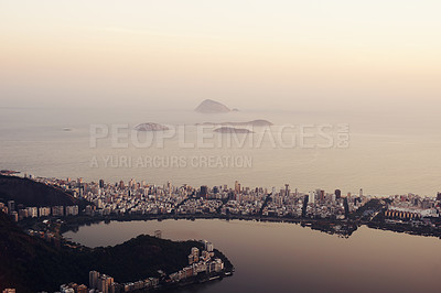 Buy stock photo Drone, city and landscape at sunset with ocean, coast or water in background in urban Rio de Janeiro. Brazil, lagoon and cityscape with mountain on holiday for travel on vacation with sea on horizon