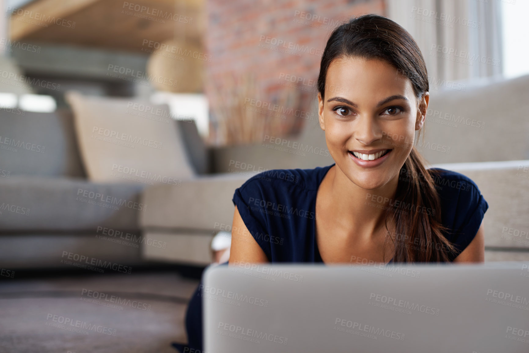 Buy stock photo Shot of an attractive young woman using her laptop while relaxing on the floor at home