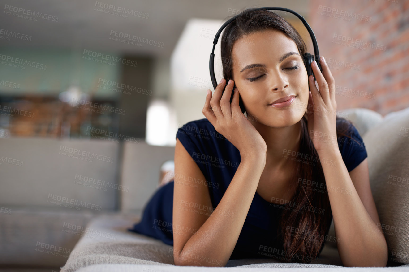 Buy stock photo Face, music and peace with woman on sofa in living room of home to relax for free time break. Headphones, radio and audio with young person lying on couch in apartment for weekend chilling or rest
