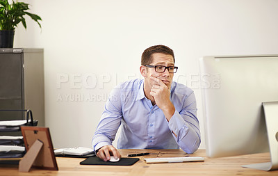 Buy stock photo Shot of a businessman looking uncertain as he works on his computer
