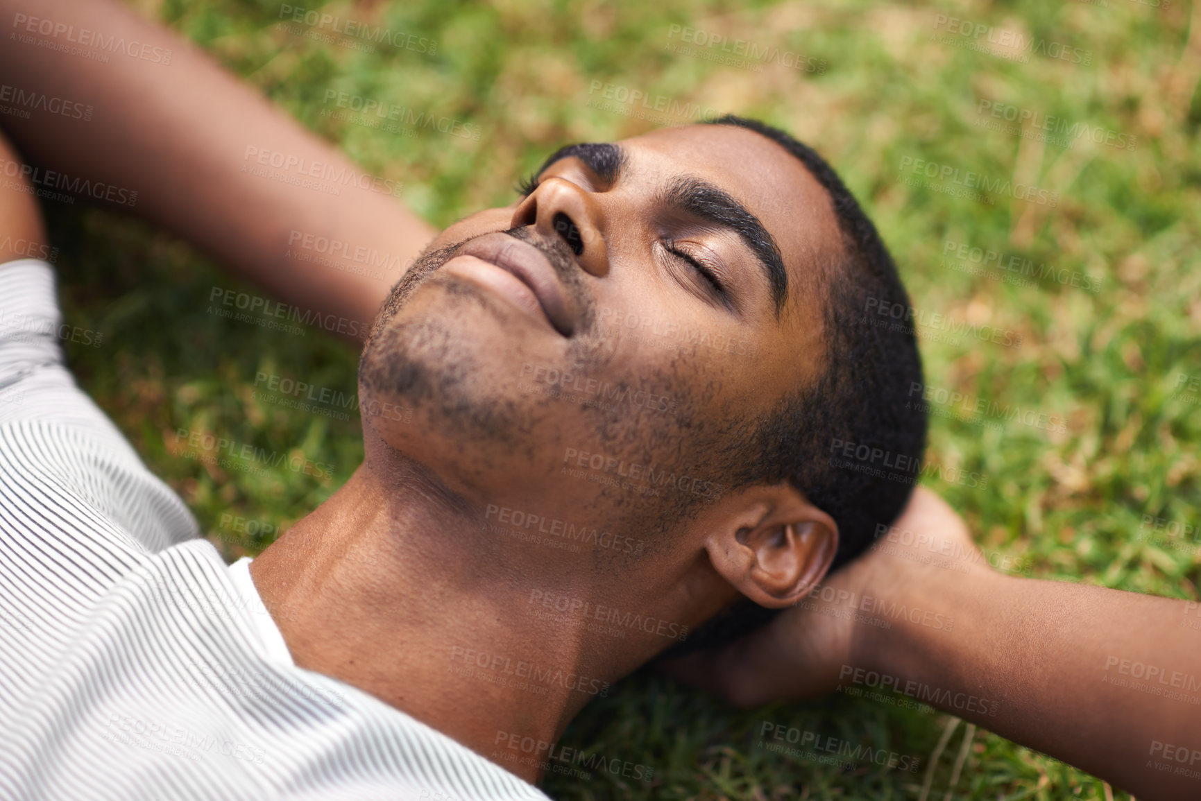 Buy stock photo Face, relax and black man on grass in garden of summer home for peace, wellness or mindfulness. Nature, field and sunshine with happy young person lying on green ground from above for break or rest