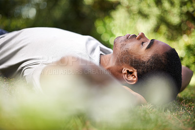 Buy stock photo Cropped shot of a handsome young man lying on the grass outdoors