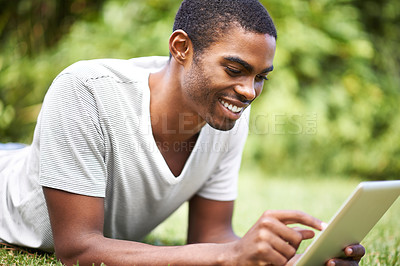 Buy stock photo Man, smile and tablet on grass to relax, African male person and mobile streaming from technology. Social media, online entertainment or internet web browsing, fun or happy in nature for calm weekend