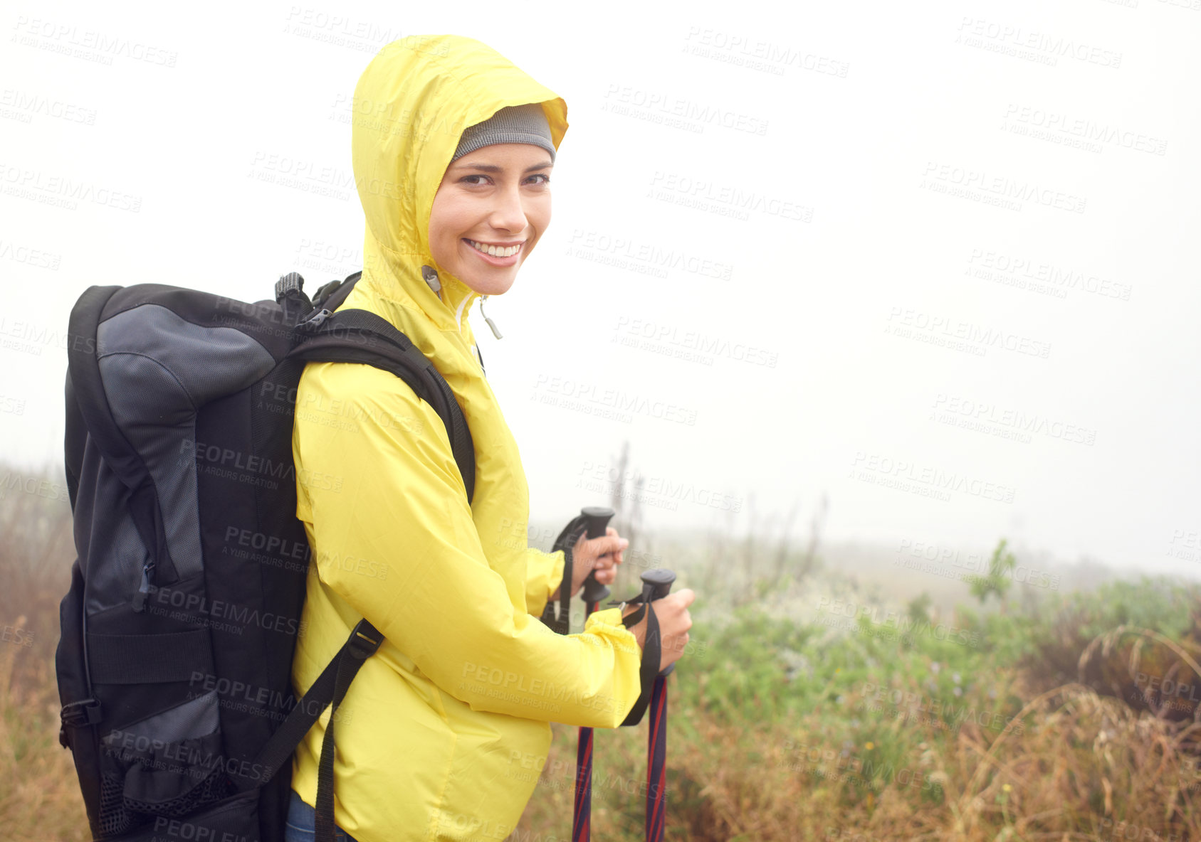 Buy stock photo Portrait, woman hiker and smile on mountain trail, exercise and cardio for fitness in nature. Fog, walking stick and gear for training and morning overcast weather, workout and happy or rest on path