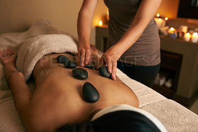 Buy stock photo A young woman receiving hot stone therapy at the spa