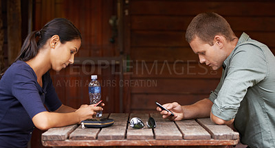 Buy stock photo Two young adults being distracted by technology while out on a coffee date
