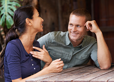 Buy stock photo A young couple chatting while sitting at a cafe