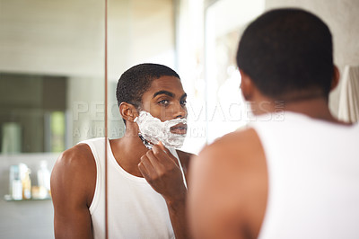 Buy stock photo Black man, mirror and shaving with razor in bathroom for grooming, skincare or morning routine. Reflection, beard or person with cream on face for cleaning, health or hair removal for hygiene in home