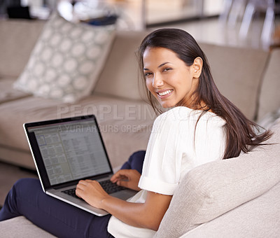 Buy stock photo Shot of an attractive young woman sitting on the couch with her laptop
