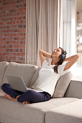 Buy stock photo Shot of an attractive young woman listening to music on her laptop at home