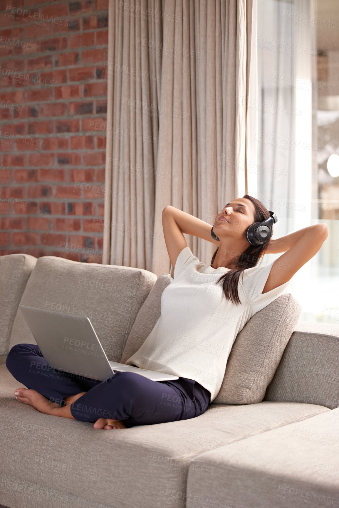 Buy stock photo Shot of an attractive young woman listening to music on her laptop at home