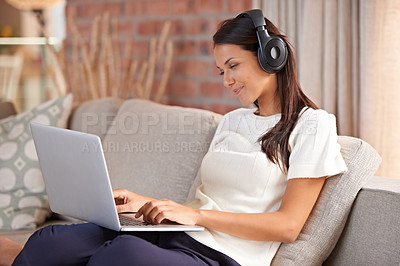 Buy stock photo Home, headphones and a woman typing on a laptop and listening to music or audio while streaming online. Happy female person relax on sofa to listen to radio or watch a movie with internet connection