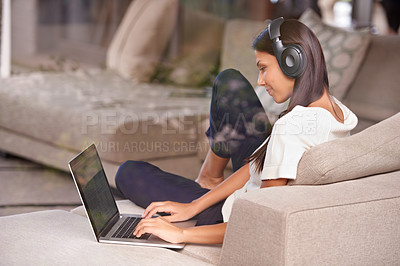 Buy stock photo Headphones, typing and woman with laptop on home sofa listening to music, audio or streaming movies. Happy female student relax on couch to listen to podcast or research to learn language on internet