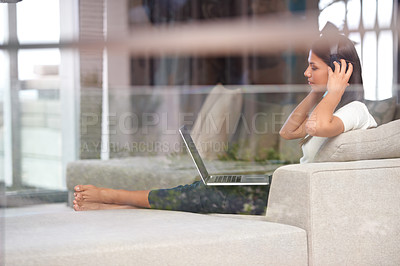 Buy stock photo Woman, headphones and a laptop for internet on a home sofa while listening to music or streaming audio. Female student relax on couch to listen to radio channel, podcast or learn language online
