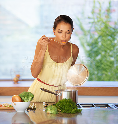 Buy stock photo A young woman tasting her homemade soup