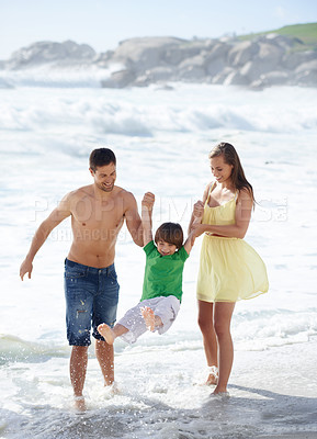 Buy stock photo Family, summer and swinging child at beach for fun, travel or holiday with a smile in water. A man, woman and kid or son playing together on vacation at sea with waves, love and happiness outdoor
